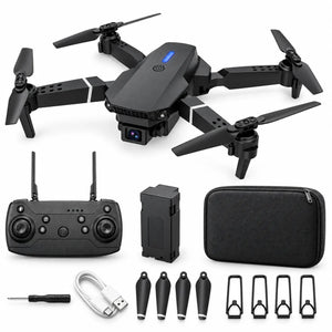 Black quadcopter drone with four propellers, shown with a handheld remote controller, battery pack, carrying case, USB charging cable, screwdriver, four spare propeller blades, and four mounting brackets on a white background.